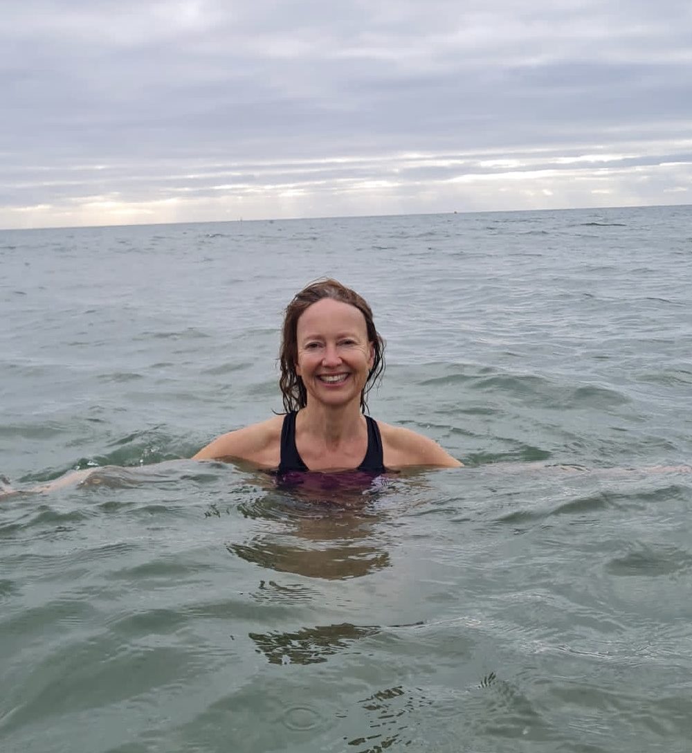 Woman enjoys cold water therapy swimming in the sea in Dorset